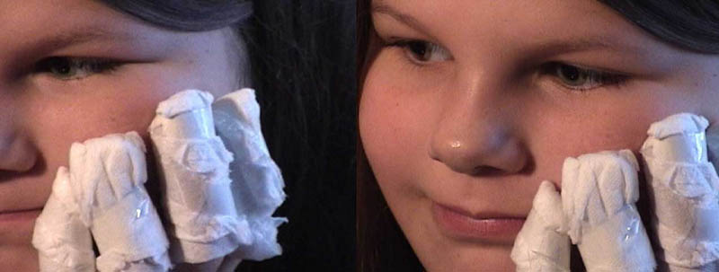 video still of a young girl wearing self-made bandages on her fingers. The bandages are fashioned out of toiletpaper and scotch tape